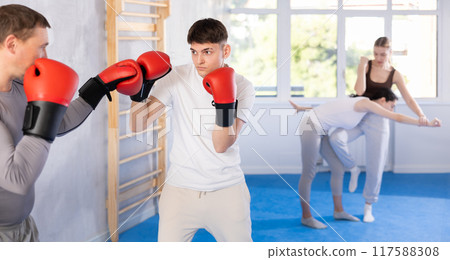 Two boxers in sportswear are engaged in boxing sparring in gym Two boxers in sportswear are engaged in boxing sparring in gym 117588308