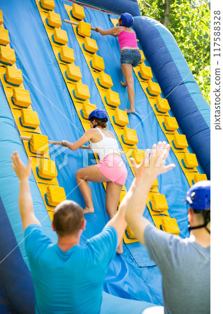 Women climbing up on slide in adventure park Women climbing up on slide in adventure park 117588328