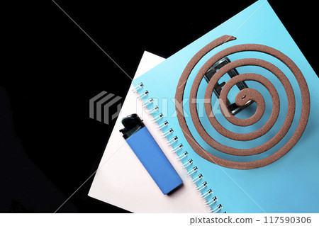 A blue notebook with a mosquito coils on it 117590306
