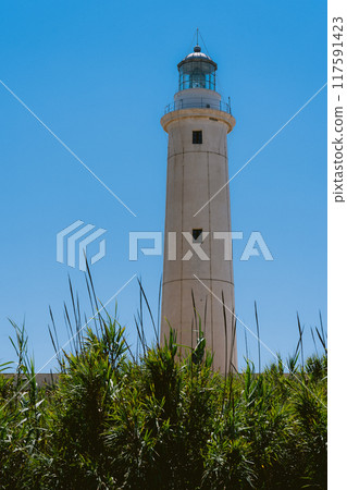 A coastal lighthouse shining against the blue sky 117591423