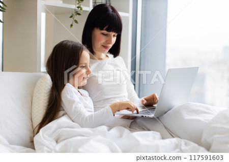 Mother and daughter bonding while using laptop in bed Mother and daughter bonding while using laptop in bed 117591603
