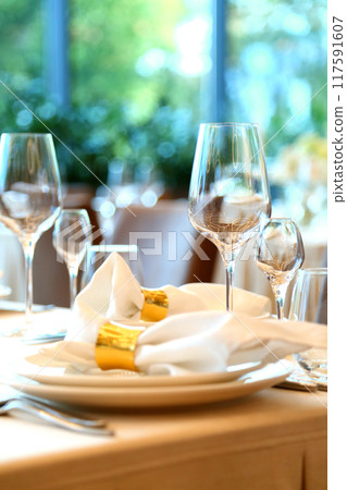 Table setting in a restaurant. Empty glasses set in restaurant. Table setting with glasses, cutlery and plates. Restaurant interior. Table setting in a restaurant. Empty glasses set in restaurant. Table setting with glasses, cutlery and plates. Restaurant interior. 117591607