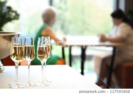 Champagne on the table at the restaurant. Champagne on a table in a restaurant with people sitting in the background. Champagne on the table at the restaurant. Champagne on a table in a restaurant with people sitting in the background. 117591608