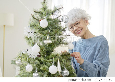 Senior woman decorating Christmas tree with ornaments Senior woman decorating Christmas tree with ornaments 117592039