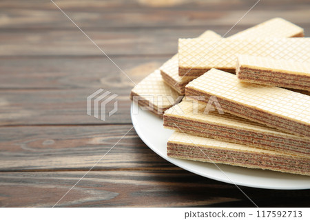Chocolate wafers on plate on brown background 117592713