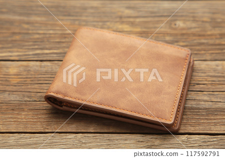 Brown shiny wallet on grey wooden background Brown shiny wallet on grey wooden background 117592791