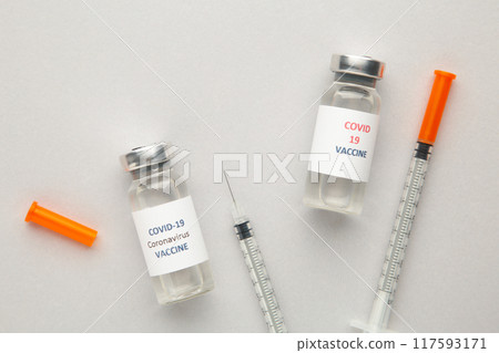 Coronavirus COVID-19 vaccine vials and syringe on grey background with copy space. Coronavirus COVID-19 vaccine vials and syringe on grey background with copy space. 117593171