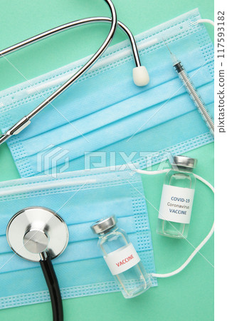 Coronavirus COVID-19 vaccine vials, syringe and stethoscope on mint background. Vaccination session and immunity improvement. Covid 19 Coronavirus COVID-19 vaccine vials, syringe and stethoscope on mint background. Vaccination session and immunity improvement. Covid 19 117593182