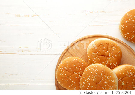 Burger buns on cutting board on a white wooden background. Burger buns on cutting board on a white wooden background. 117593201