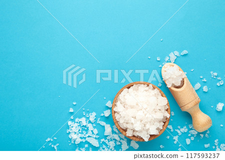 Sea salt in bowl and spoon on blue background 117593237