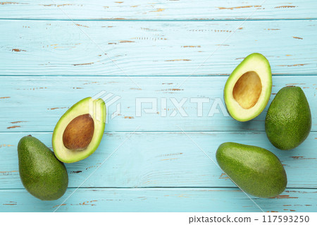 Fresh avocado and half of avocado on blue background Fresh avocado and half of avocado on blue background 117593250
