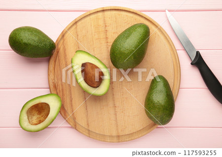 Avocado on a cutting board on pink table Avocado on a cutting board on pink table 117593255