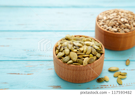 Pumpkin and sunflower seeds in bowl on blue wooden background. Pumpkin and sunflower seeds in bowl on blue wooden background. 117593482