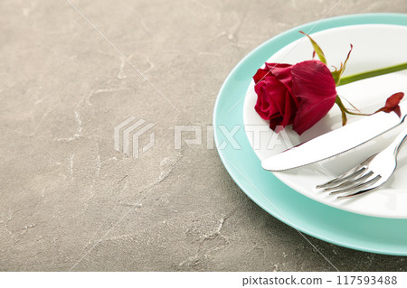 Romantic restaurant table setting with red rose on plates on grey 117593488