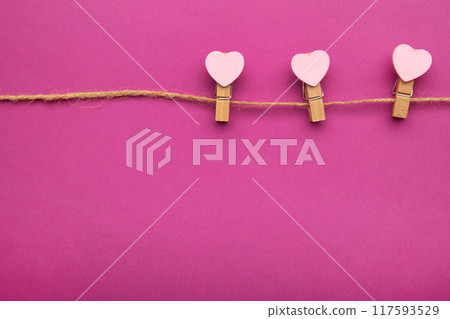 Pink hearts on rope with clothespins, on a pink background. Top 2021. 117593529