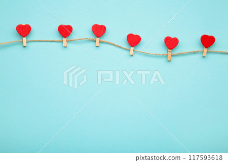 Red hearts on rope with clothespins, on a blue background. Top 2021. Red hearts on rope with clothespins, on a blue background. Top 2021. 117593618