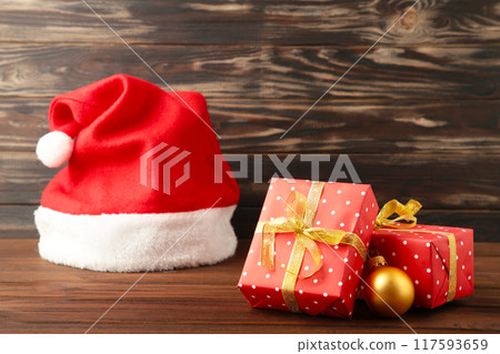 Christmas gifts with santa hat on brown background. Christmas gifts with santa hat on brown background. 117593659