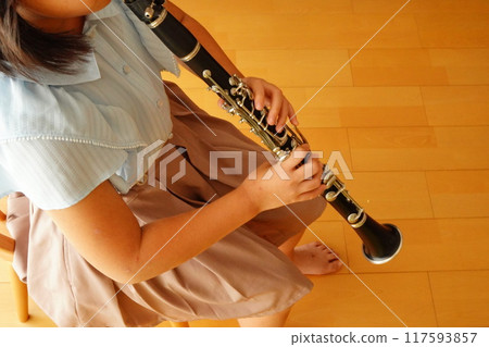 An elementary school girl who plays the clarinet in the brass band. She practices at home. 117593857