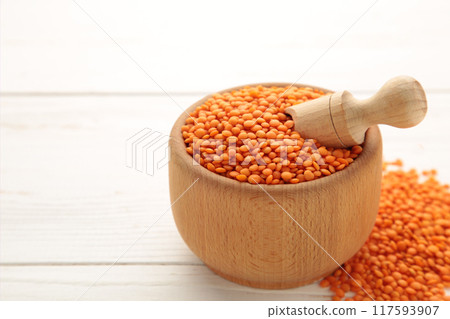 Red lentils in a wooden spoon and bowl on white background. 117593907