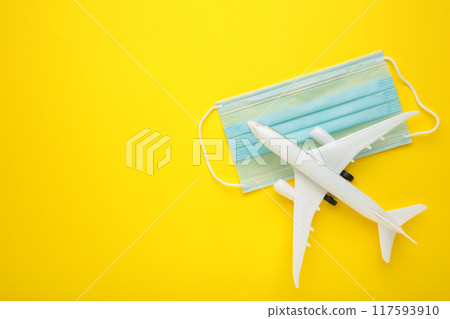 Medical mask against coronavirus with airplane on yellow background. Travel concept 117593910