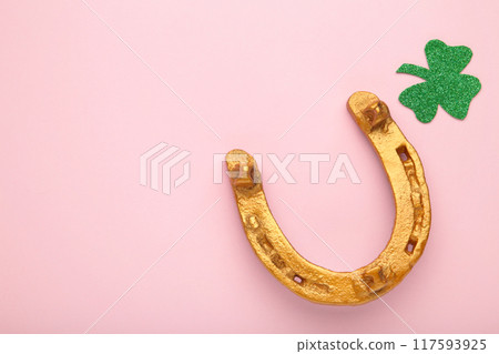 Green clover and gold horseshoe on pink background for St. Patrick's Day Holiday. 117593925