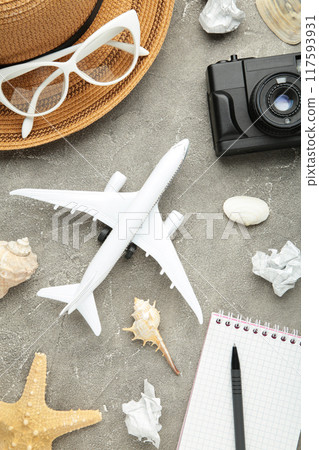 Airplane with traveler accessories on grey background. Travel concept. Vertical foto Airplane with traveler accessories on grey background. Travel concept. Vertical foto 117593931