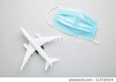 Medical mask against coronavirus with airplane on grey background. Travel concept 117593934