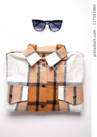 Multi-colored checkered women's shirt lying neatly folded on a light background 117593960