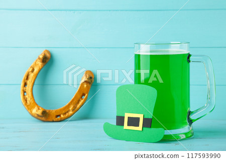 Glass of beer and horseshoe for St Patricks day on blue background 117593990