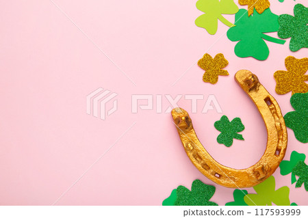 Green clovers and gold horseshoe on pink background for St. Patrick's Day Holiday. Green clovers and gold horseshoe on pink background for St. Patrick's Day Holiday. 117593999