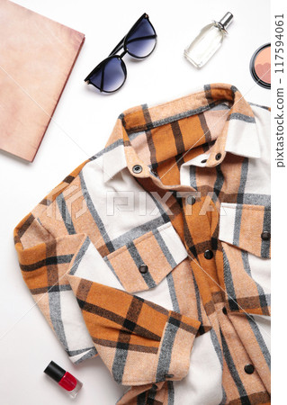 Multi-colored checkered women's shirt with accessories on a light background Multi-colored checkered women's shirt with accessories on a light background 117594061