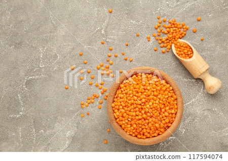 Red lentils in a wooden spoon and bowl on grey background. 117594074