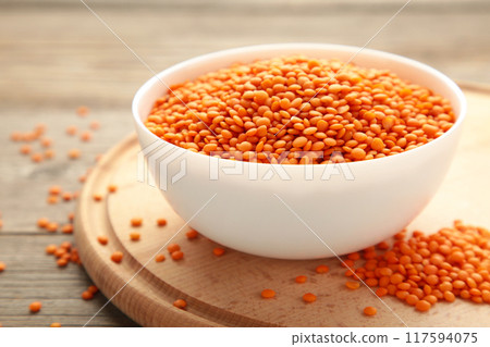 Red lentils in white bowl on a grey wooden table. Red lentils in white bowl on a grey wooden table. 117594075