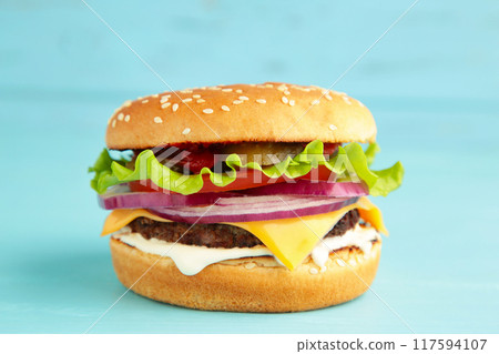 Homemade hamburger with vegetables on blue background. Homemade hamburger with vegetables on blue background. 117594107