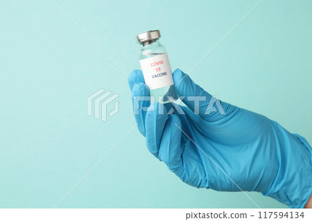 Medical doctor holding tube with Coronavirus vaccine for 2019-nCoV COVID virus on blue background. 117594134