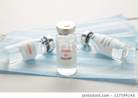 Coronavirus COVID-19 vaccine vials and hygiene protective face mask on grey background. Coronavirus COVID-19 vaccine vials and hygiene protective face mask on grey background. 117594148