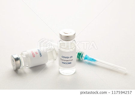 Coronavirus COVID-19 vaccine vials and syringe on grey background with copy space. Coronavirus COVID-19 vaccine vials and syringe on grey background with copy space. 117594257