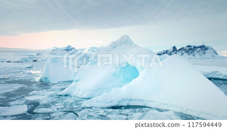 Frozen Arctic ice floes winter landscape. Icebergs floating cold polar ocean, mountains range in background. Antarctica glacier seascape close up. Ecology, climate change. Travel background panorama 117594449
