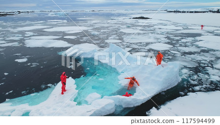 People on large floating ice iceberg in Antarctica. Scientists from polar station expedition outdoor. Icy landscape, melting glacier, wild nature of South Pole. Aerial shot 117594499