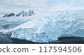Blue snowy glacier towering Antarctica coastline. Snow covered giant iceberg ice wall rises above cold, dark ocean water. Antarctic winter polar landscape panorama. Aerial cinematic ecology scene 117594506