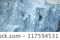 Close up calving glacier ice cliff dominates polar ocean. Towering blue snow wall mountain in background. Natural wild scene, winter wallpaper. Ecology, melting ice, climate change and global warming 117594531