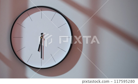 Elegant Black Clock Showing 18.30/06.30 with Shadows on Minimalist Wall - Ideal for Time Management and Interior Design Promotions 117595280