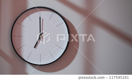 Elegant Black Clock Showing 19.00/07.00 with Shadows on Minimalist Wall - Ideal for Time Management and Interior Design Promotions Elegant Black Clock Showing 19.00/07.00 with Shadows on Minimalist Wall - Ideal for Time Management and Interior Design Promotions 117595281