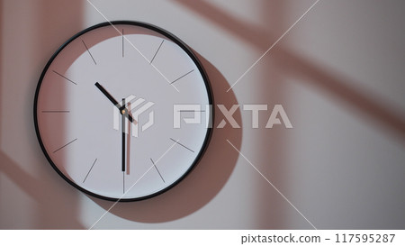 Elegant Black Clock Showing 22.30/10.30 with Shadows on Minimalist Wall - Ideal for Time Management and Interior Design Promotions Elegant Black Clock Showing 22.30/10.30 with Shadows on Minimalist Wall - Ideal for Time Management and Interior Design Promotions 117595287