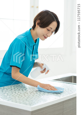 A woman from a housekeeping service cleaning the kitchen A woman from a housekeeping service cleaning the kitchen 117595715