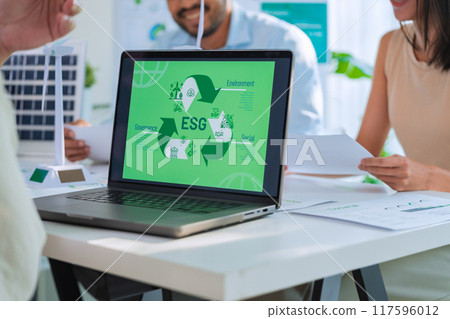 diversity team brainstorming focused on ESG (environment,social,governance)  with tablet or sdgs goals in a sustainable green office at night 117596012