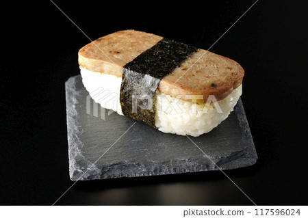 Spam musubi on a slate plate photographed against a black background Spam musubi on a slate plate photographed against a black background 117596024