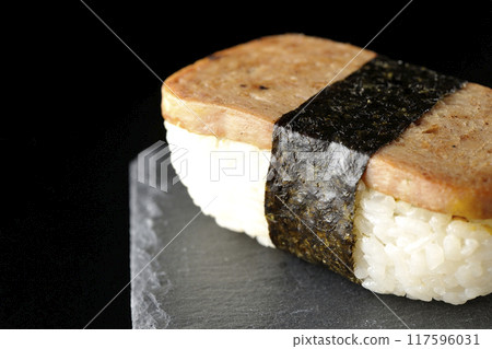 Spam musubi on a slate plate photographed against a black background Spam musubi on a slate plate photographed against a black background 117596031