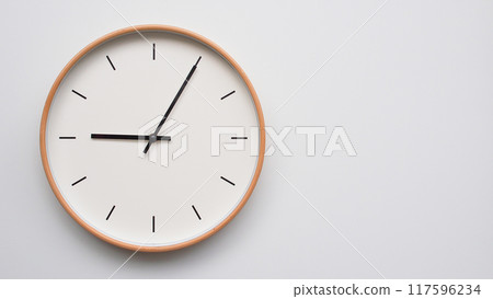 Minimalist wooden Wall Clock on White Wooden Surface with Space for Text.  Time Set at 21.05/09.05 117596234