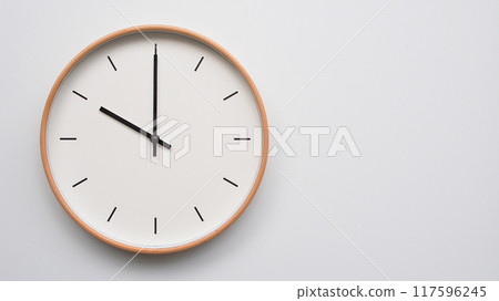 Minimalist wooden Wall Clock on White Wooden Surface with Space for Text.  Time Set at 117596245